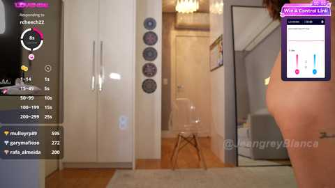 Media: Video of a modern bedroom with white walls, wooden floor, and a glass door. A mirror on the left displays a user's live stream with a heart icon.