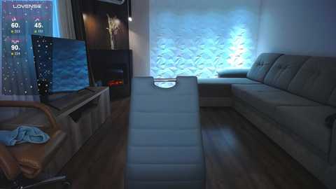 Media: Video of a modern living room with a TV displaying a weather forecast, beige sofa, cushioned recliner, and a textured white wall with blue lighting.