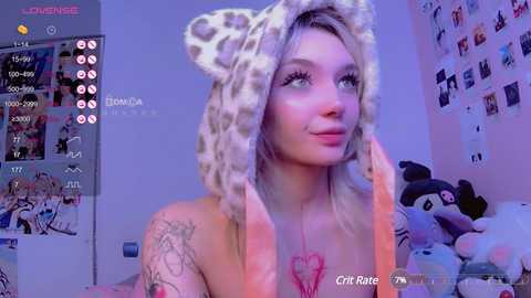 Media: A video of a fair-skinned, tattooed woman in a leopard-print hood, looking seductively at the camera in a bedroom with pastel-colored walls and stuffed toys.