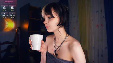 Media: A video of a young woman with short black hair, fair skin, and a delicate build, holding a white mug, standing in a dimly lit room with a wooden chair and bookshelf in the background.