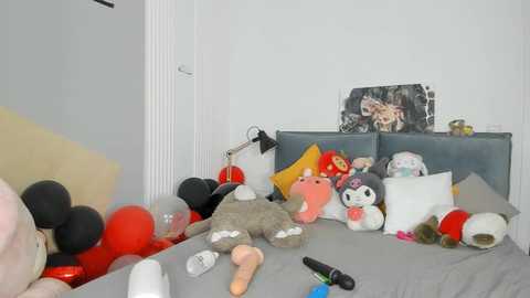 Media: A messy bedroom with a gray bed, stuffed animals, red balloons, a black lamp, and scattered items on the floor.