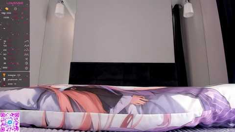 Media: Video of a bedroom with a large bed covered in a colorful anime duvet featuring a character lying down, surrounded by modern wall-mounted lights.