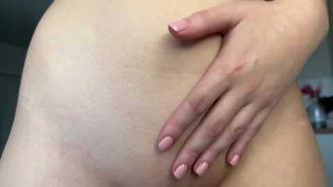 Media: A close-up video of a light-skinned person's lower abdomen, showing stretch marks and a hand with neatly manicured nails resting on the skin. The background is blurred and indistinct.