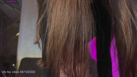 Media: Video of a person with long, wavy brown hair, styled with a straightening iron, showing sleek, smooth texture. Background features blurred purple and white colors.