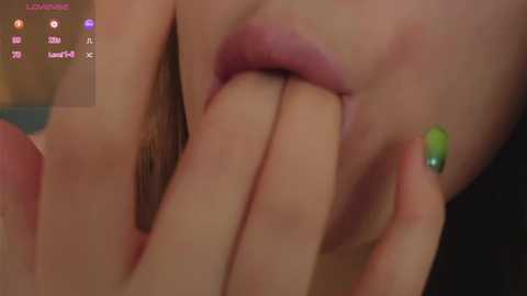 Media: Close-up video of a woman's lips, with a man's fingers gently touching her mouth. Her lips are slightly parted, revealing her tongue, and she has a green nail polish on her index finger.