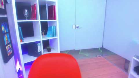 Media: Video of a modern, minimalist office with white walls, wooden floor, a red chair, and a white desk with a computer monitor.