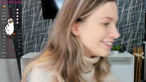 Media: A video of a smiling, light-skinned woman with long, blonde hair, wearing a cream-colored sweater, against a gray, abstract wall. A virtual avatar of a penguin appears in the top left corner.