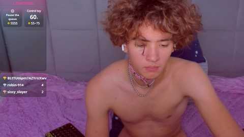 Media: Video of a shirtless, skinny young man with curly brown hair, wearing headphones and a pink choker, lying on a purple bed.