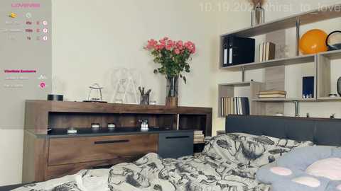 Media: Video of a modern, minimalist bedroom featuring a wooden dresser, glass vase with flowers, and shelves with books and decor.