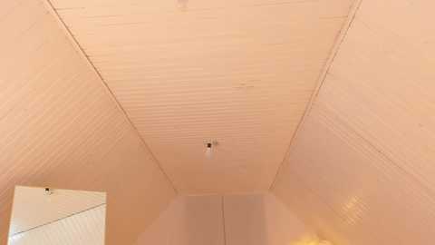 Media: Video of a narrow, cream-colored, ribbed ceiling with a central light fixture, leading to a white, paneled wall with a recessed area. The space has a minimalist, modern aesthetic.