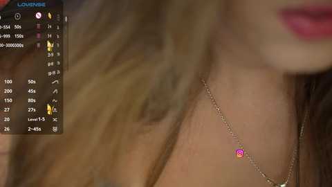 Media: Close-up video of a woman's neck adorned with a delicate silver chain necklace featuring a small, colorful Instagram logo charm. Background is blurred, focusing on the jewelry.