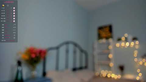 Media: A blurred video of a cozy, softly lit bedroom with pastel blue walls, a floral arrangement, and a mirrored vanity with string lights.