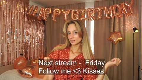 Media: Video of a blonde woman in a red-patterned dress holding a birthday balloon. She stands in a room with gold tinsel and \"Happy Birthday\" banner. Text overlay: \"Next stream - Friday, Follow me <3 kisses.\