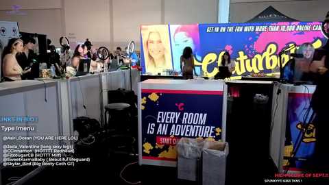 Media: Video of a lively event featuring a colorful backdrop with a \"Cinderella\" theme, multiple screens showing characters and text, and a diverse crowd watching from behind tables.