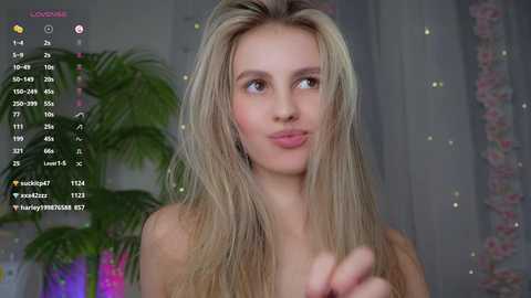 Media: A video of a nude blonde woman with fair skin and long hair, looking contemplative, with a digital overlay of social media statistics.