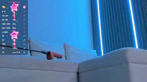 Media: Video of a modern, minimalist living room with a white sectional couch and blue curtains. A red screwdriver is inserted into the couch's upholstery, with a smartphone displaying a star rating app on the left side.