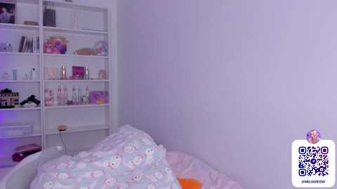 Media: Video of a minimalist bedroom with white walls, a white bookshelf filled with colorful toiletries, and a bed covered in pastel-patterned sheets. A QR code is in the bottom right corner.