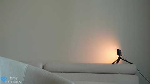 Media: Video of a minimalist room with a white couch and a small lamp emitting a warm, soft glow, creating a serene and cozy ambiance.