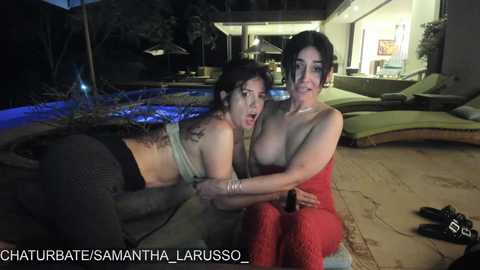 Media: Video of two women, one with dark curly hair in a bikini, the other with short dark hair topless, at a nighttime poolside party.