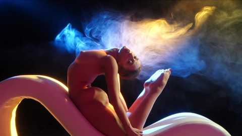 Media: Video of a nude, muscular, light-skinned man with short hair, performing a split while levitating above a glowing, white, snake-like creature. He is surrounded by blue and orange smoke, creating a mystical, ethereal atmosphere.