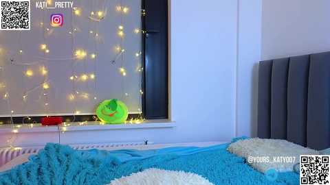 Media: Video of a bedroom with a blue bedspread, white pillow, and a large window with fairy lights and a green pillow. Text and QR codes in the top corners.