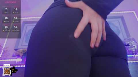 Media: A video of a person with fair skin, wearing tight black leggings, standing in a dimly lit room with purple LED strip lights. The person's hand is on their hip, showcasing the curve of their buttocks.