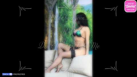 Media: A blurred video of a woman in black lingerie and thigh-high stockings, sitting on a cream couch, with a lush green forest background.