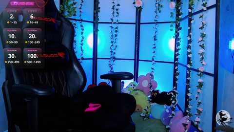 Media: Video of a virtual reality setup with a black gaming chair, a headset, and a green and purple plush toy, surrounded by string lights and hanging plants, with a digital interface showing health and ammo levels.