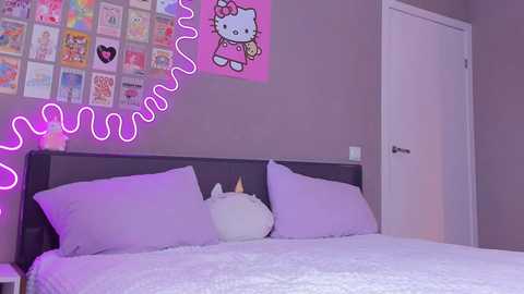 Media: Video of a modern bedroom with a dark wooden headboard, white bedding, and a large Hello Kitty poster. Neon pink \"Hello Kitty\" text on the wall.