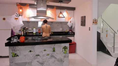 Media: Video of a modern kitchen with a black marble island, stainless steel appliances, and a person in a yellow shirt cooking.