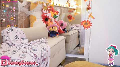 Media: Video of a cozy living room with a beige sofa, stuffed toys, a white blanket, and large floral decorations. The room's reflection in a mirror adds depth. Watermark \"SunnySonic\" and a character illustration in the bottom right.