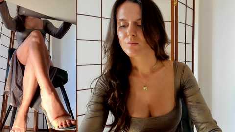 Media: Video of a Caucasian woman with long brown hair, wearing a low-cut olive green top, sitting on a wooden chair. Her legs are crossed, revealing a black high-heeled shoe. Background includes a folding screen with a mirror reflecting her upper body.