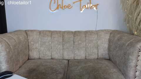 Media: Video of a beige, plush sectional sofa with a tufted design, featuring a gold \"Chloe Totoro\" sign on a white wall. The sofa has a cozy, textured feel.