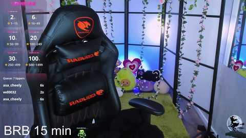 Media: A video of a black gaming chair with red logos, set in a cozy room with pastel decor, featuring plush toys and a soft green rug.