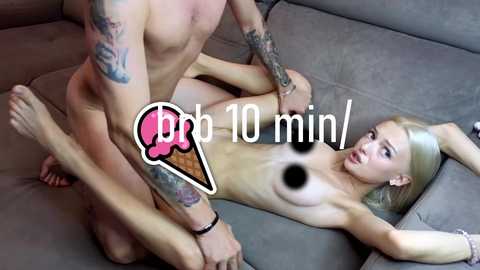 Media: A video shows a nude tattooed man penetrating a nude blonde woman with large breasts on a grey couch. The image includes a \"bb 10 min\" watermark.