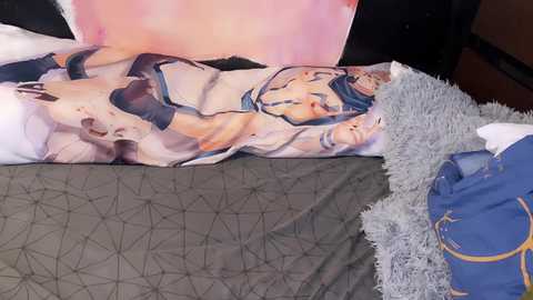 Media: Video of a person sleeping on a bed with a blanket featuring a romantic anime scene. The person is in blue pajamas and a fluffy gray pillow is visible.