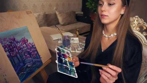 Media: Video of a young woman with long brown hair, seated at a table, painting vibrant flowers on canvas with a palette and brush. She wears a black dress and pearl necklace, in a cozy, dimly lit room.