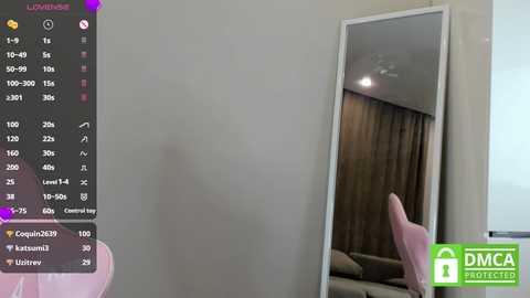 Media: Video of a modern living room with a large mirror reflecting a pink chair and beige curtains. A smartphone screen on the left displays app icons and a video call.