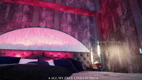 Media: Video of a modern, dimly-lit bedroom with a tufted, pink velvet headboard, a large arched mirror, and a sleek, metallic lamp on a nightstand.