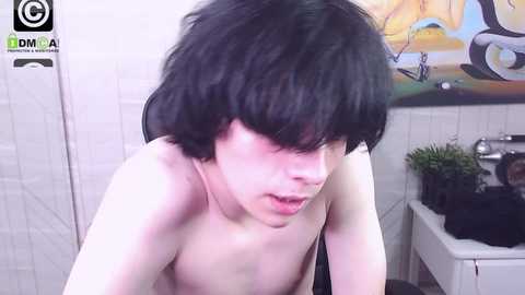 Media: Video of a pale, shirtless man with black, messy hair, leaning over a bathtub in a tiled bathroom with a colorful mural.