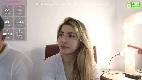 Media: A video of a blonde woman in a white top, seated in an office, with a large calendar and a lamp in the background.