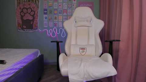 Media: Video of a white gaming chair with \"ASUS\" logo, surrounded by a cluttered bedroom with a unmade bed, pastel-colored walls, and a wall of colorful stickers.