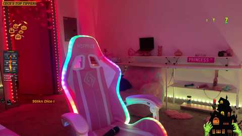 Media: Video of a cozy, pink-lit gaming room featuring a white gaming chair with rainbow LED lighting, a desk with \"Princess\" sign, and various gaming accessories.