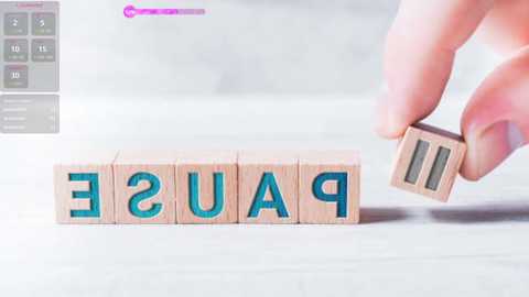 Media: A video shows a hand holding a wooden block with the word \"PAUSE\" in teal letters. In the background, a digital display indicates a countdown from 10 to 1. The setting appears minimalist with a white floor.