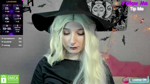 Media: Video of a young woman with long, platinum blonde hair wearing a black witch hat and dark makeup, with a live stream overlay showing DMCAs and Tip Me buttons.