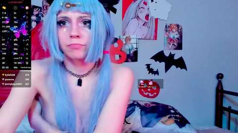 Media: A video of a pale-skinned, blue-haired woman with bangs, topless, wearing a black choker, in a room adorned with Halloween decorations, including a jack-o'-lantern and bat cutouts.