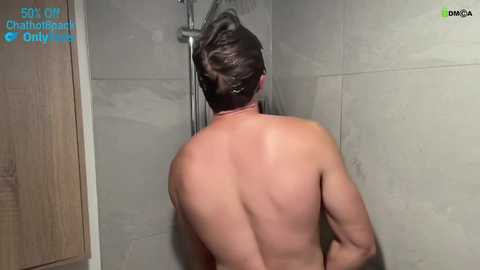 Media: Video of a shirtless man with short dark hair showering in a beige-tiled bathroom. Text overlays read \"5k+ Chaturbate Champs\" and \"OnlyFans.\