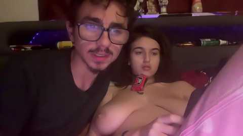 Media: Video of a man with glasses and mustache, and a topless woman with a red Pop-Tart in her mouth, sitting on a couch.