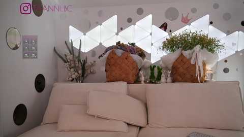 Media: Video of a modern living room with a white couch, large white diamond-shaped window, and decorative potted plants, including a basket with a floral arrangement, on the backrest.