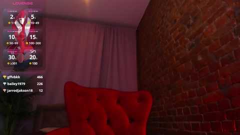 Media: Video of a dimly lit room with a red velvet armchair, exposed brick wall, and a digital screen displaying a red-haired anime character, likely a gaming stream.